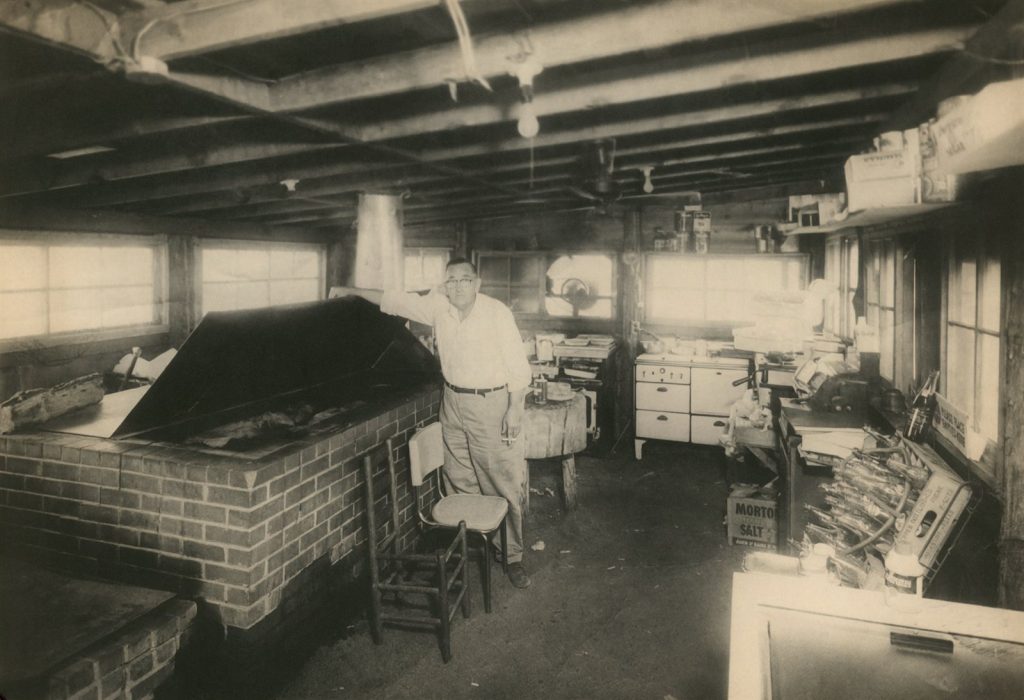Samuel Augustus Daniel standing at the brick barbecue pit inside the original Sam's, Fairfield, Texas.